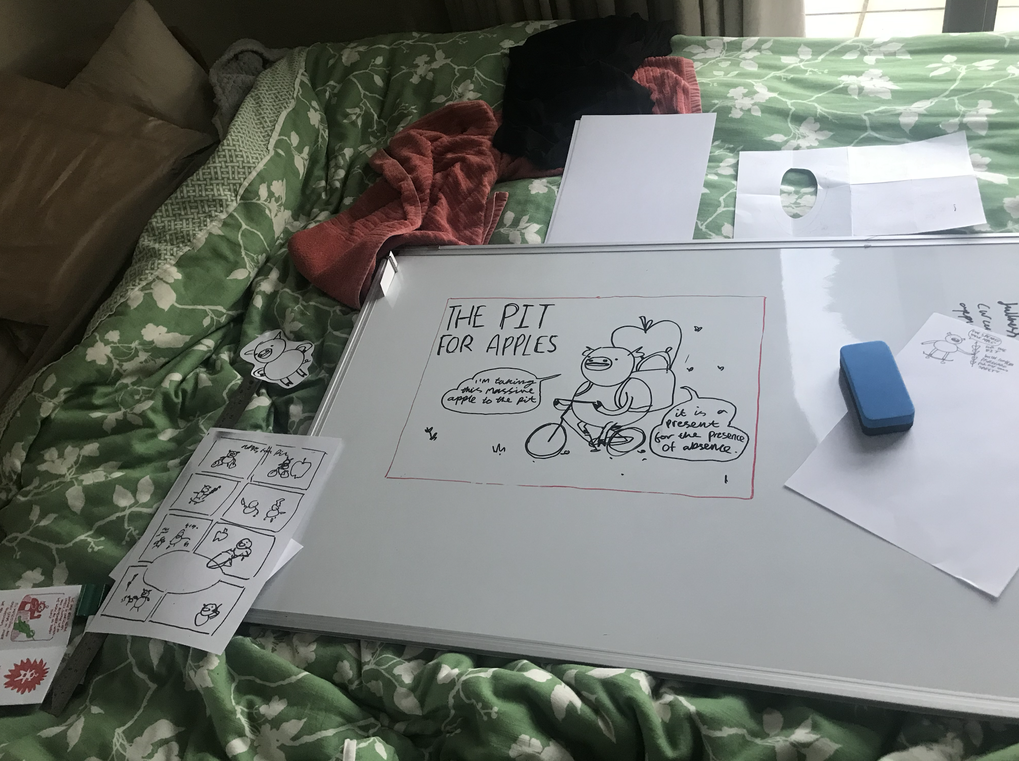 a bed with a whiteboard and some other bits of paper on it, all with different pictures of pigs on them