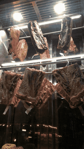 meat hanging in a window, price tags fluttering