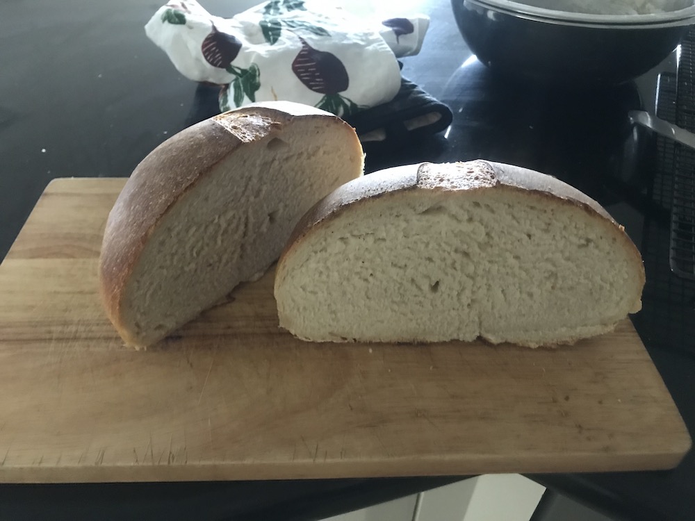 a blurry photo of a round loaf cut in half, it has a tight white crumb