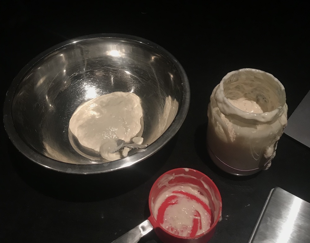 sourdough starter on the bench, spilling out the jar and a little in a bowl