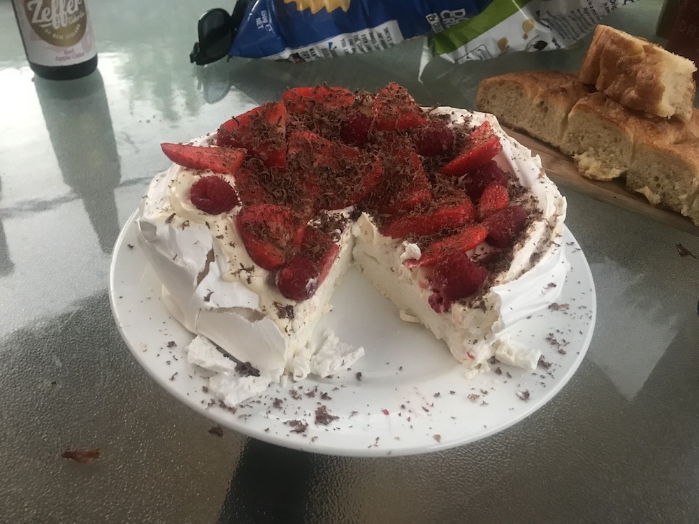a pavlova dressed with cream and berries, a slice taken out