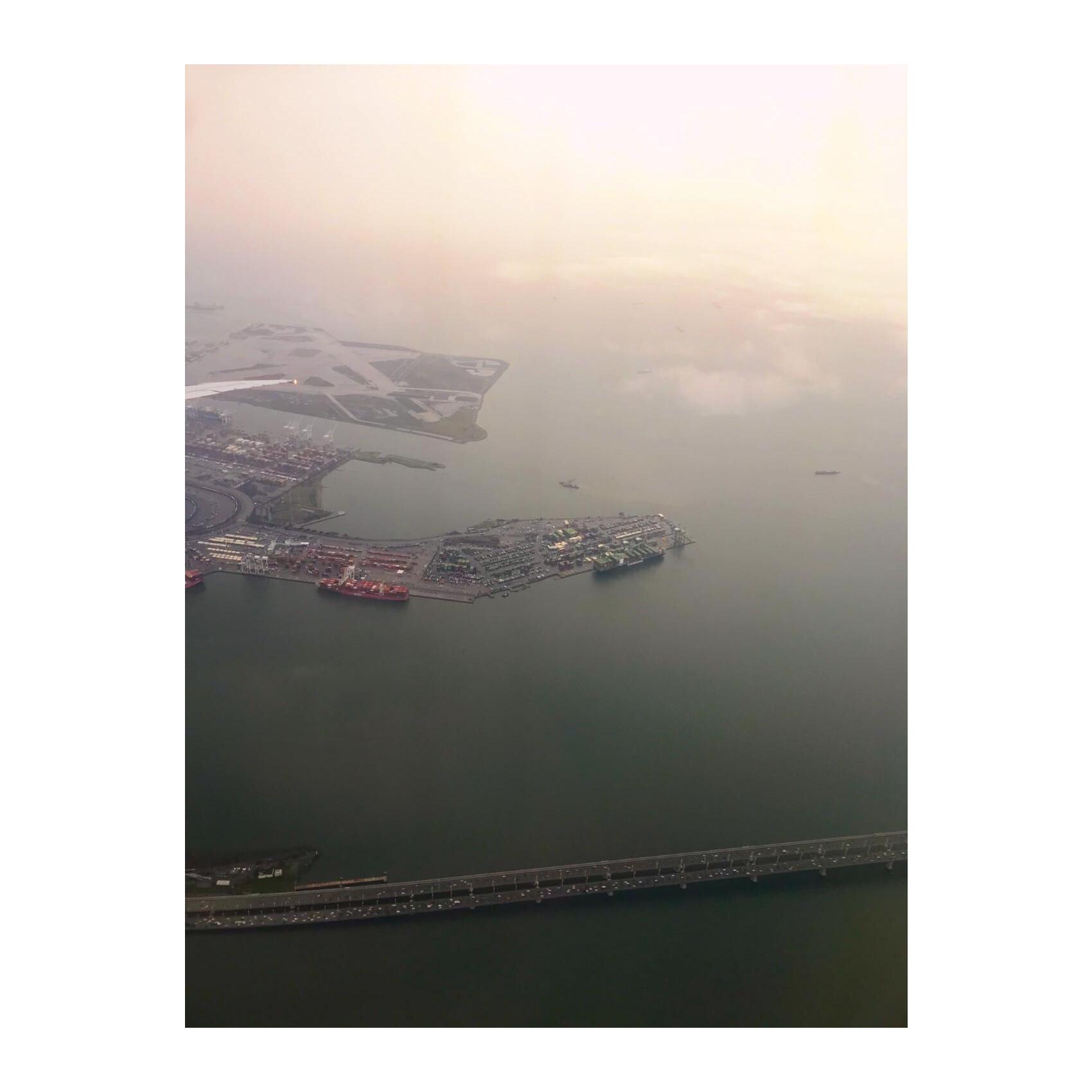 a plane window view of a port with some ships around it