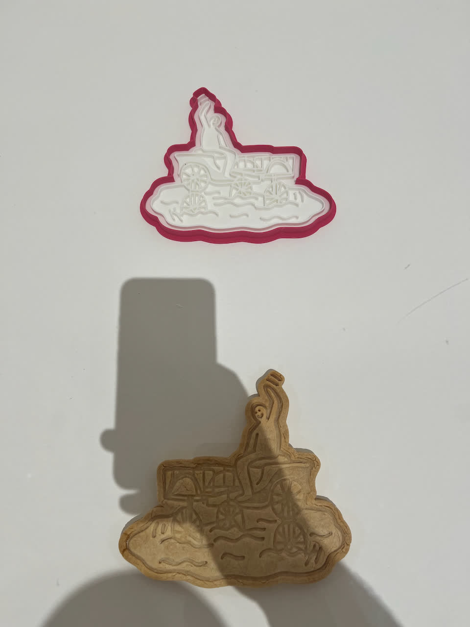 a photo of a biscuit mold made from a cartoon of a person riding a trike through a flood, and beside it the final biscuit
